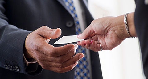 A man in a suit and tie holding a business card.